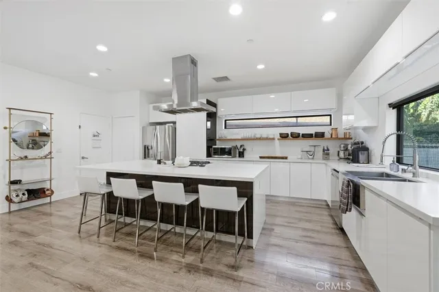 a large kitchen with stainless steel appliances a stove a refrigerator a oven a sink with a dining table and chairs with wooden floor