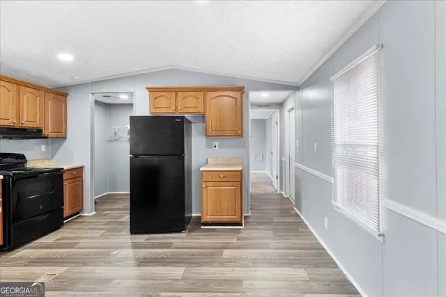 a kitchen with a refrigerator a stove top oven and cabinets