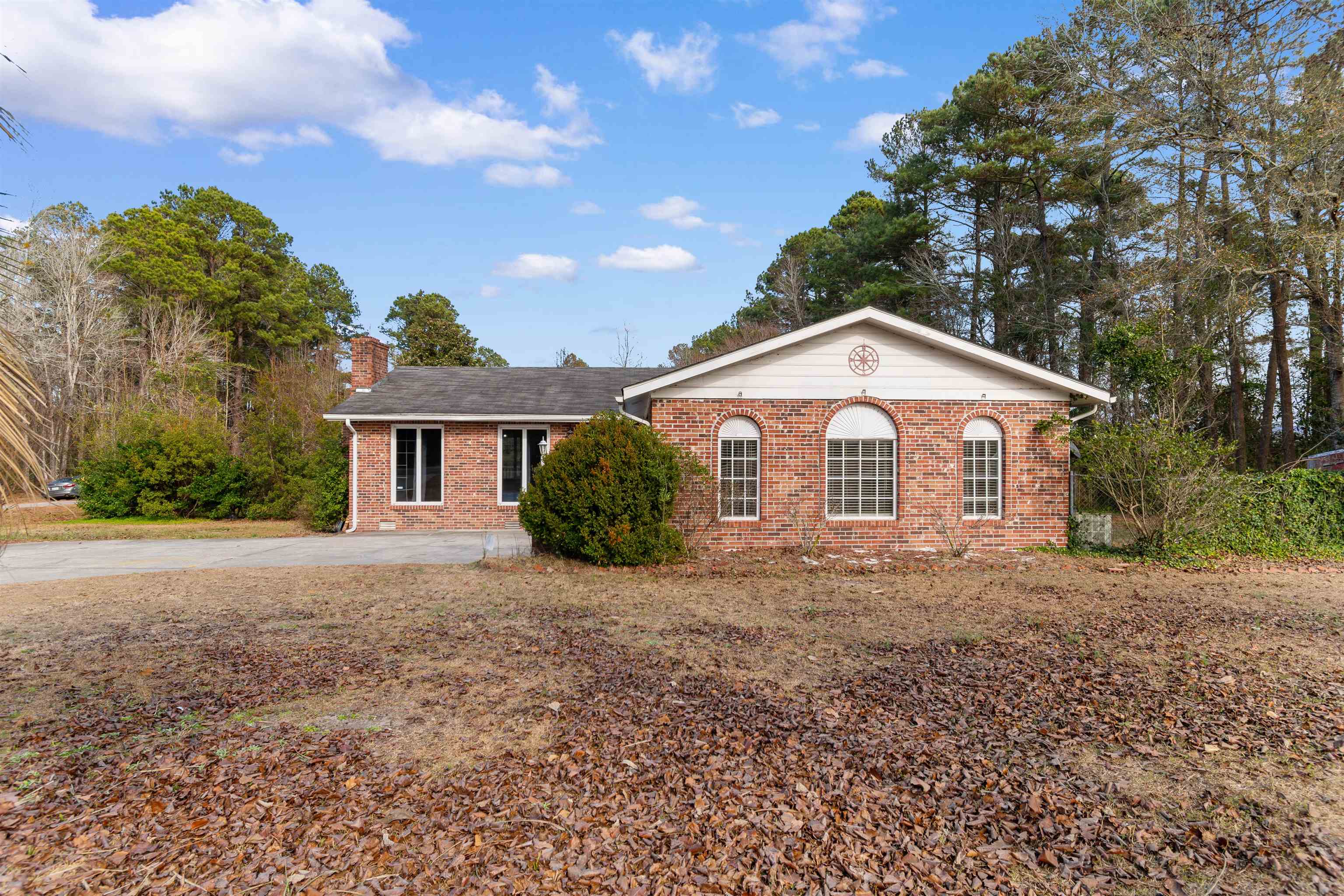 Ranch-style home with brick siding, a chimney, and driveway