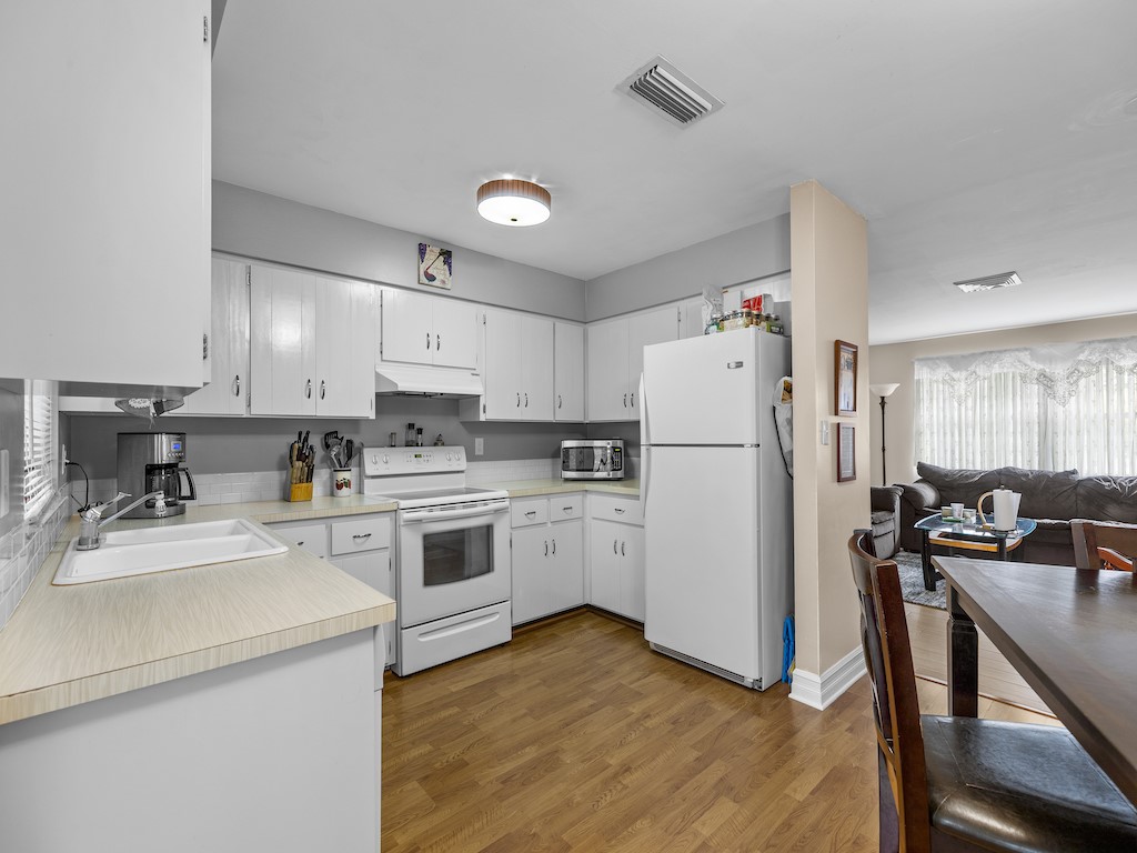 7304 Arthurs Road Fort Pierce, FL 34951 - Photo 12 of 29 a kitchen with a refrigerator a white stove top oven and white cabinets