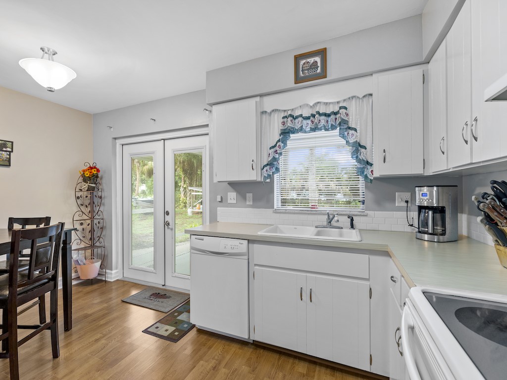 7304 Arthurs Road Fort Pierce, FL 34951 - Photo 13 of 29 a kitchen with stainless steel appliances granite countertop a stove a sink dishwasher and white cabinets with wooden floor
