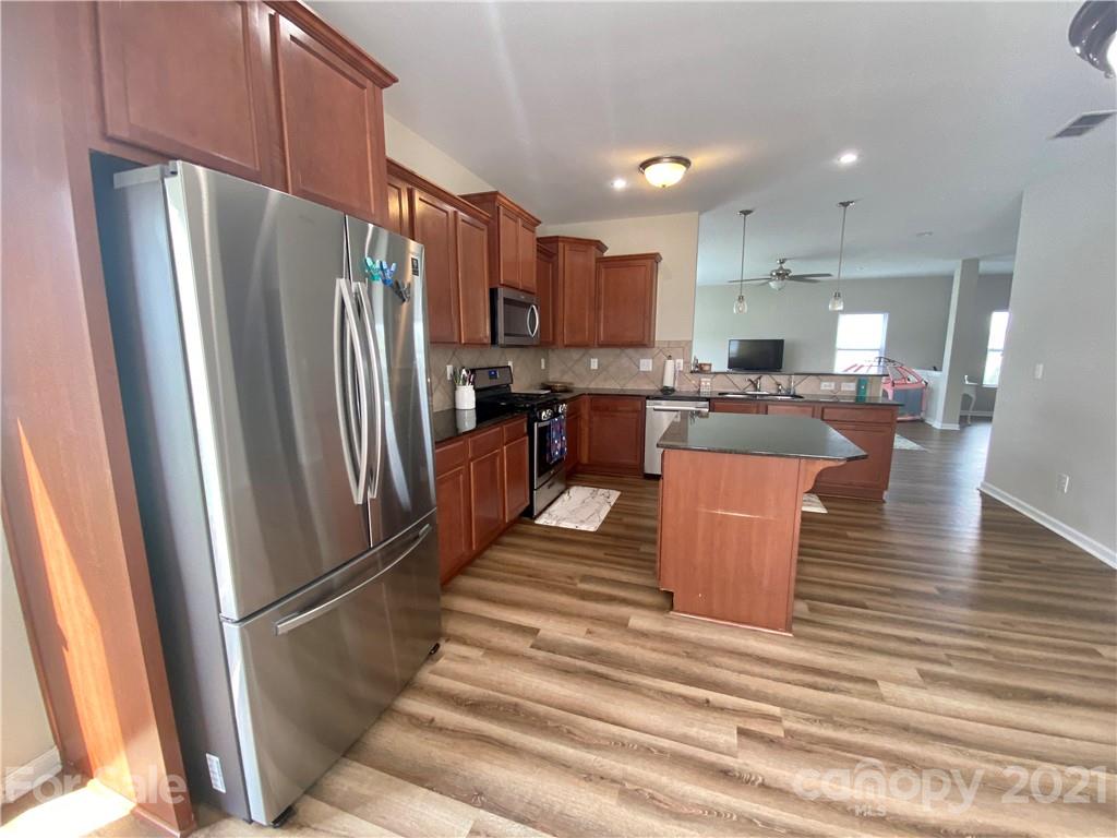 8009 Bryson Road Indian Land, SC 29707 - Photo 12 of 45 a kitchen with stainless steel appliances a refrigerator a stove a sink dishwasher with a dining table and chairs with wooden floor
