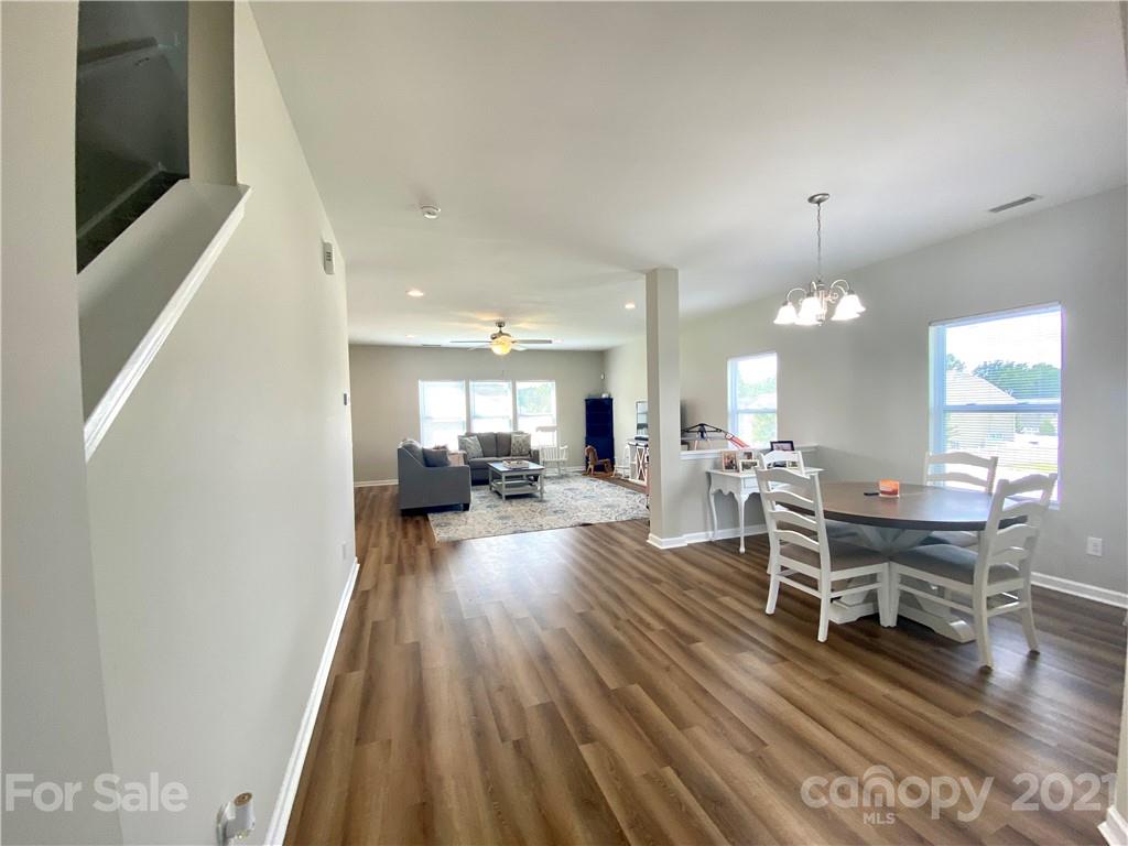 8009 Bryson Road Indian Land, SC 29707 - Photo 17 of 45 a living room with furniture a wooden floor and a chandelier