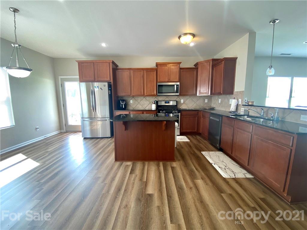 8009 Bryson Road Indian Land, SC 29707 - Photo 3 of 45 a kitchen with stainless steel appliances granite countertop a refrigerator a sink dishwasher a stove and white countertops with wooden floor