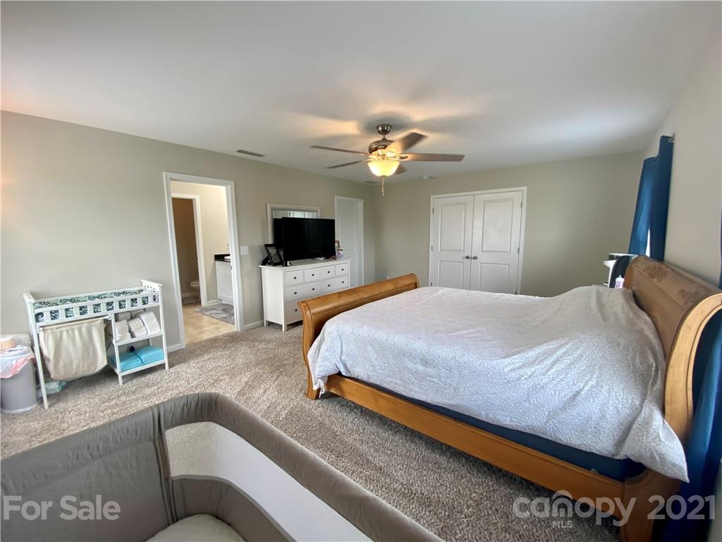 8009 Bryson Road Indian Land, SC 29707 - Photo 26 of 45 a spacious bedroom with a bed a couch and a flat screen television