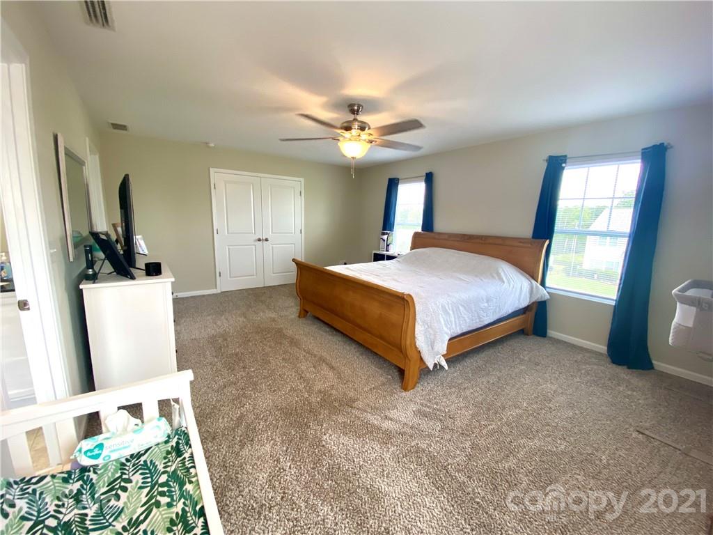 8009 Bryson Road Indian Land, SC 29707 - Photo 27 of 45 a spacious bedroom with a bed and a chandelier
