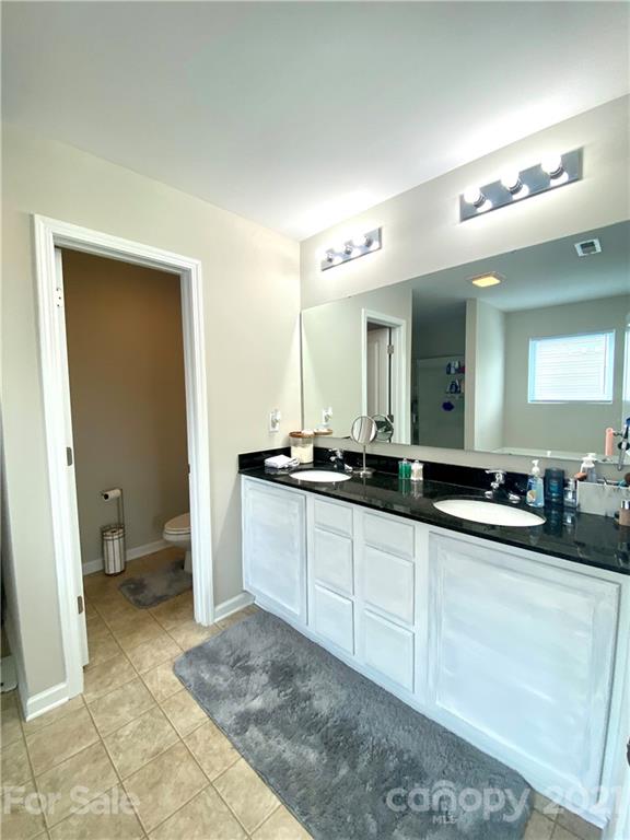 8009 Bryson Road Indian Land, SC 29707 - Photo 28 of 45 a spacious bathroom with a granite countertop sink a toilet and a mirror