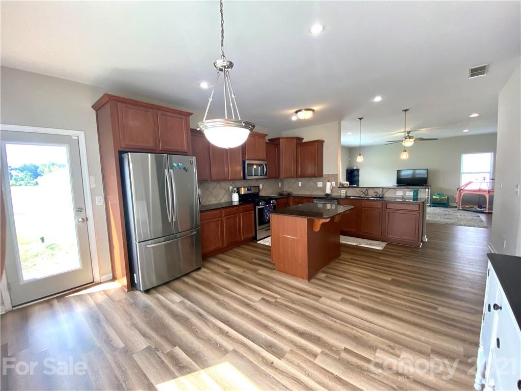 8009 Bryson Road Indian Land, SC 29707 - Photo 4 of 45 a kitchen with stainless steel appliances kitchen island granite countertop a refrigerator a stove and a wooden floors