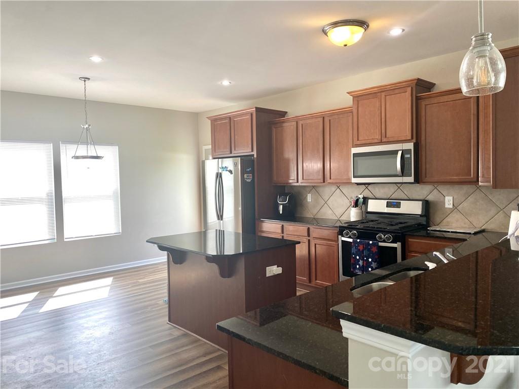 8009 Bryson Road Indian Land, SC 29707 - Photo 5 of 45 a kitchen with kitchen island granite countertop a stove top oven a sink dishwasher a dining table and chairs with wooden floor