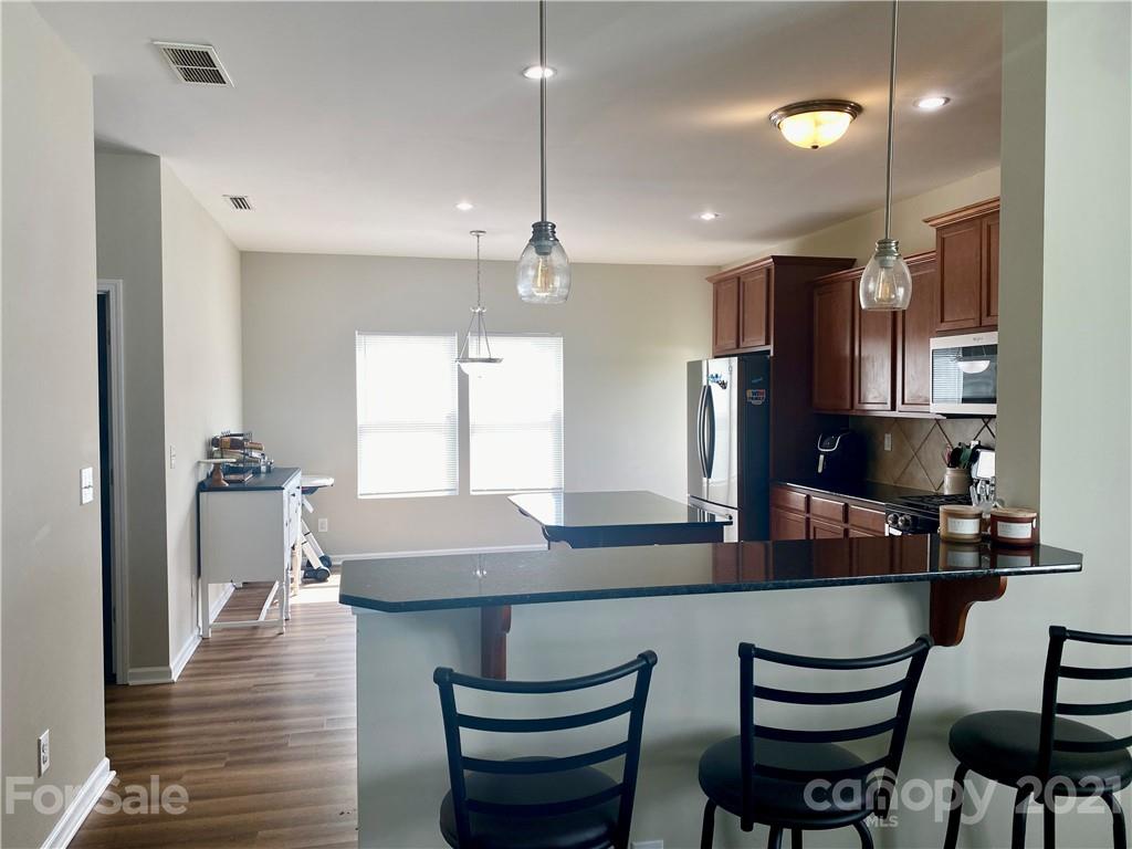 8009 Bryson Road Indian Land, SC 29707 - Photo 6 of 45 a kitchen with stainless steel appliances granite countertop a table chairs stove and refrigerator