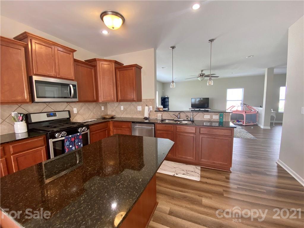 8009 Bryson Road Indian Land, SC 29707 - Photo 10 of 45 a kitchen with kitchen island granite countertop a stove top oven a sink dishwasher a dining table and chairs with wooden floor