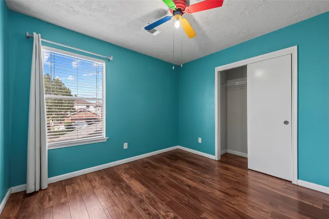 a view of empty room with wooden floor and fan