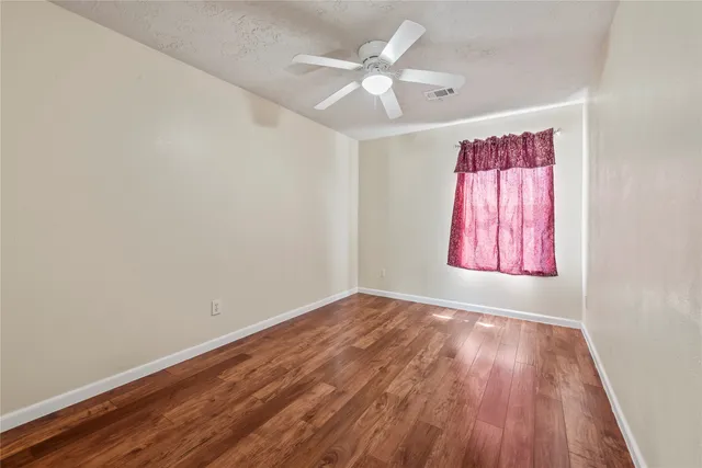 an empty room with windows and fan