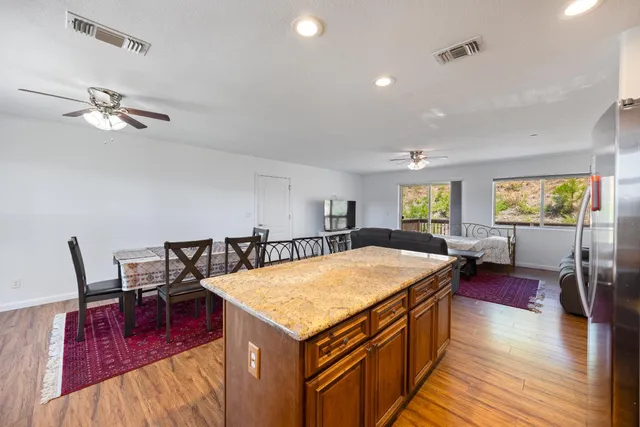 a living room with stainless steel appliances granite countertop dining table wooden floor and a rug