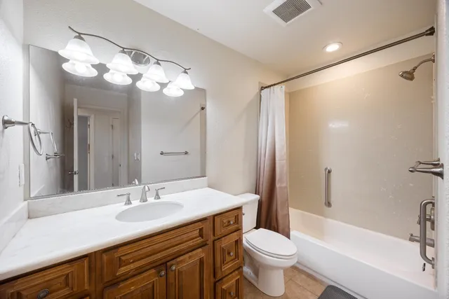 a bathroom with a sink a toilet a mirror a bathtub and shower