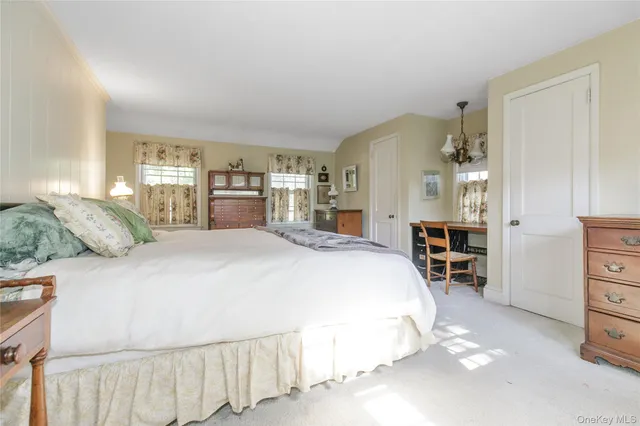 a spacious bedroom with a bed a dresser and a window