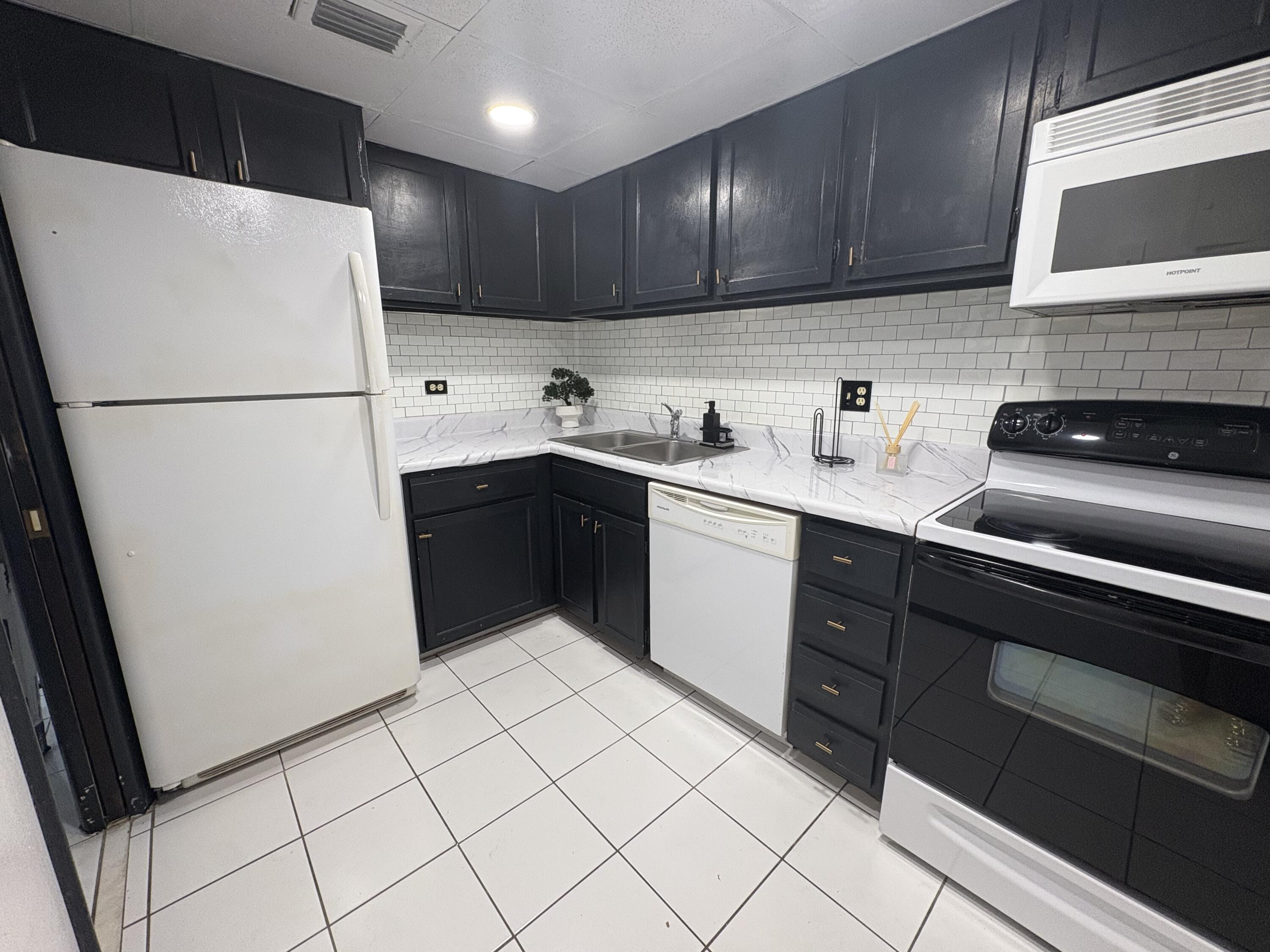 3660 Inverrary Drive, Unit 1B Lauderhill, FL 33319 - Photo 7 of 27 a kitchen with a sink a refrigerator and cabinets