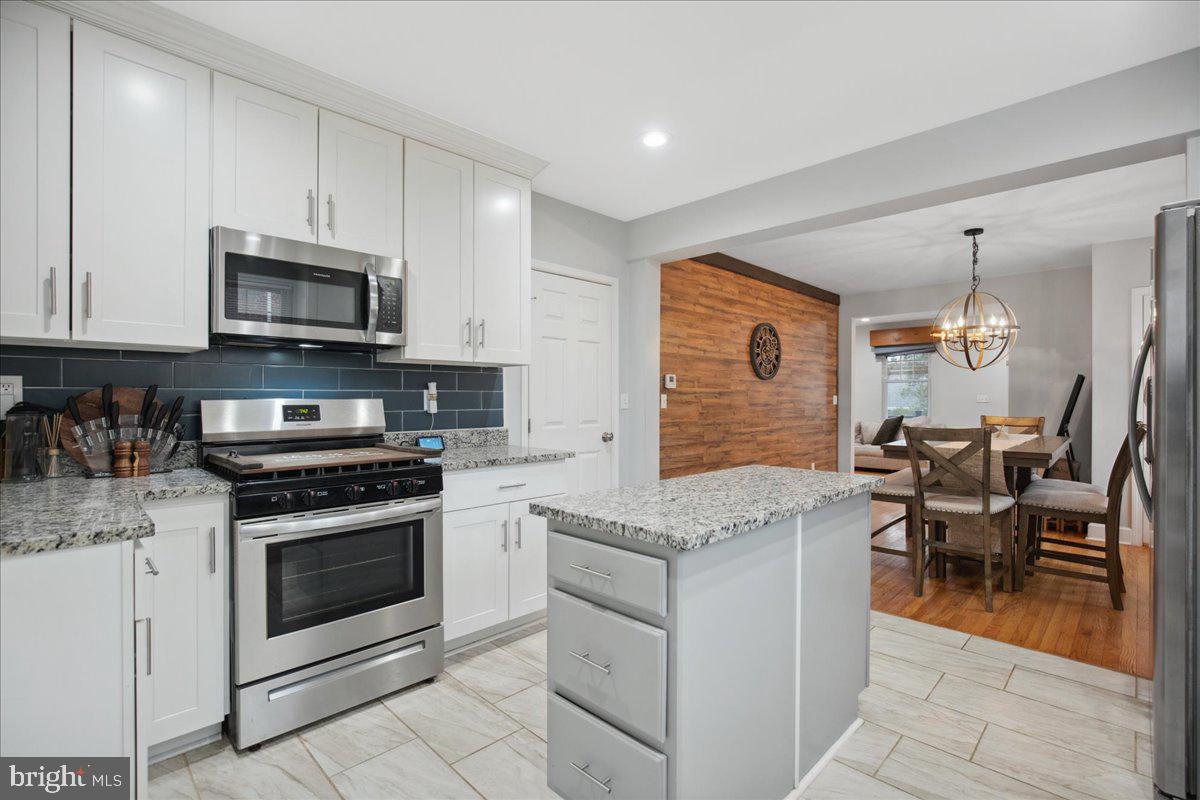 22 Cedarwood Road Catonsville, MD 21228 - Photo 17 of 44 a kitchen with stainless steel appliances granite countertop a stove top oven a sink dishwasher a dining table and chairs with wooden cabinets