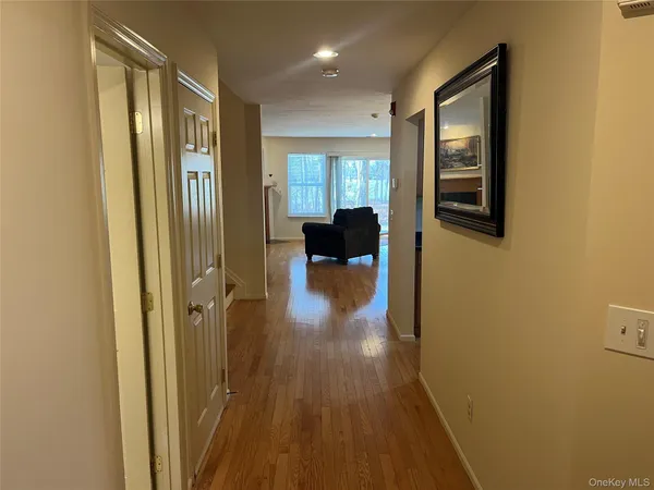 a view of a hallway with wooden floor and a bathroom