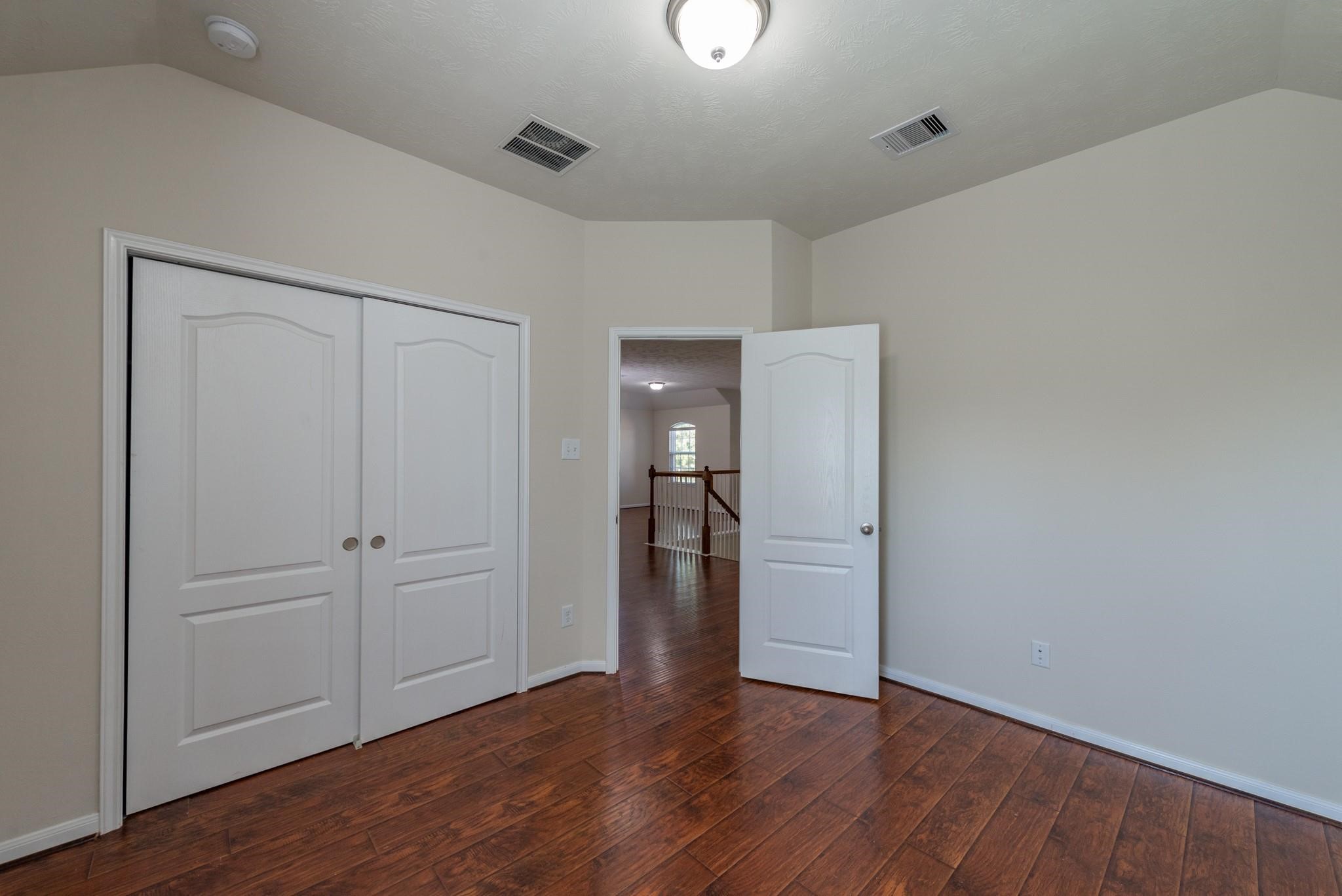 6402 Addlestone Ridge Lane Katy, TX 77494 - Photo 16 of 25 Generously sized secondary bedroom featuring rich wood-look flooring, abundant natural light, and a large closet with double doors. Ideal for family members, guests, a home office, or hobby space.