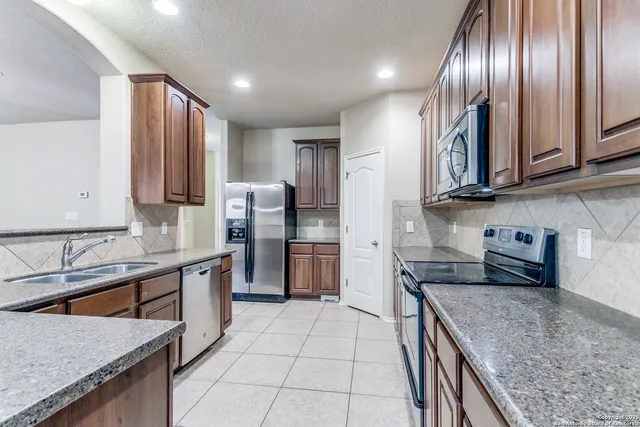 a kitchen with stainless steel appliances granite countertop refrigerator a sink a stove and cabinets