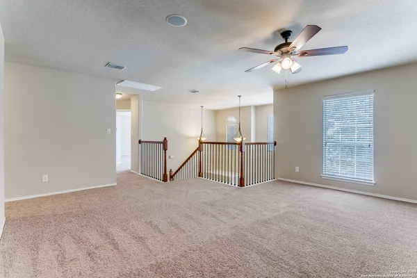 a view of an empty room with a chandelier fan