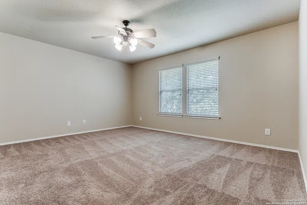 an empty room with windows and chandelier fan