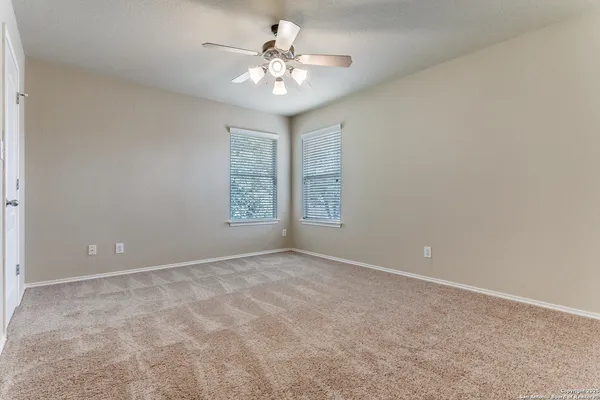 an empty room with windows and ceiling fan