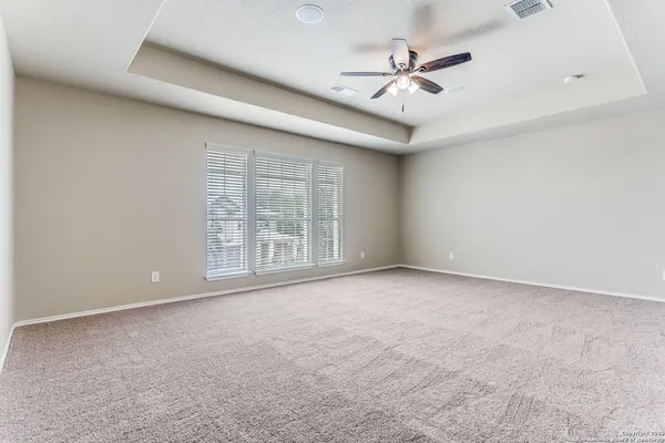 an empty room with a ceiling fan and windows