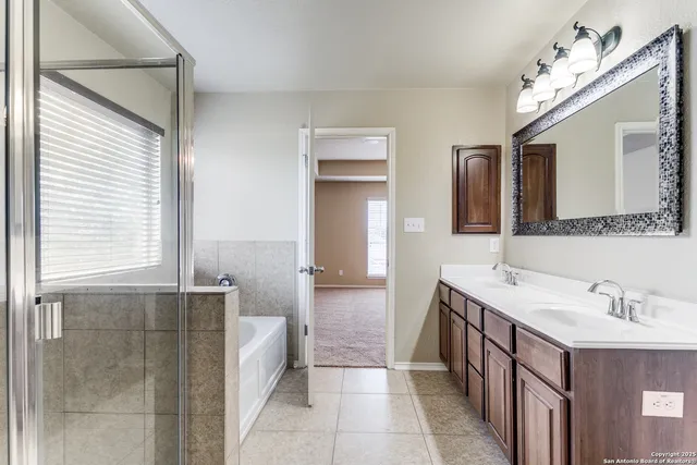 a spacious bathroom with a double vanity sink a mirror and a bathtub