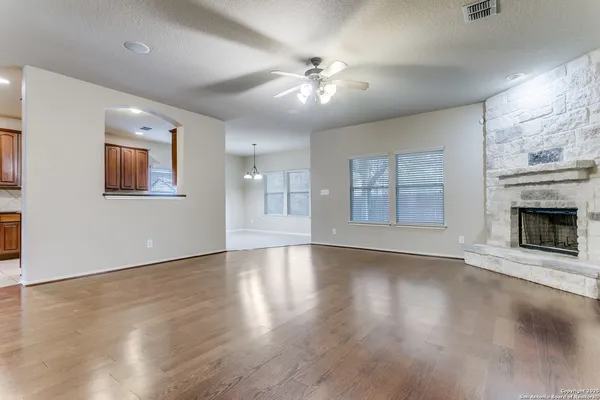 an empty room with wooden floor fireplace and windows