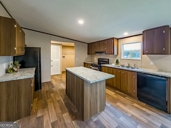 a kitchen with granite countertop a sink a counter top space and cabinets