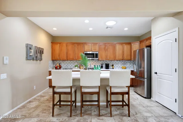 a kitchen with a dining table chairs and refrigerator