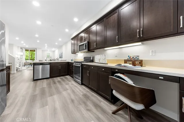 a kitchen with stainless steel appliances granite countertop wooden cabinets a sink dishwasher a stove and a refrigerator with wooden floor