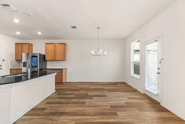 a kitchen with stainless steel appliances granite countertop a stove top oven a refrigerator a sink and dishwasher with wooden floor