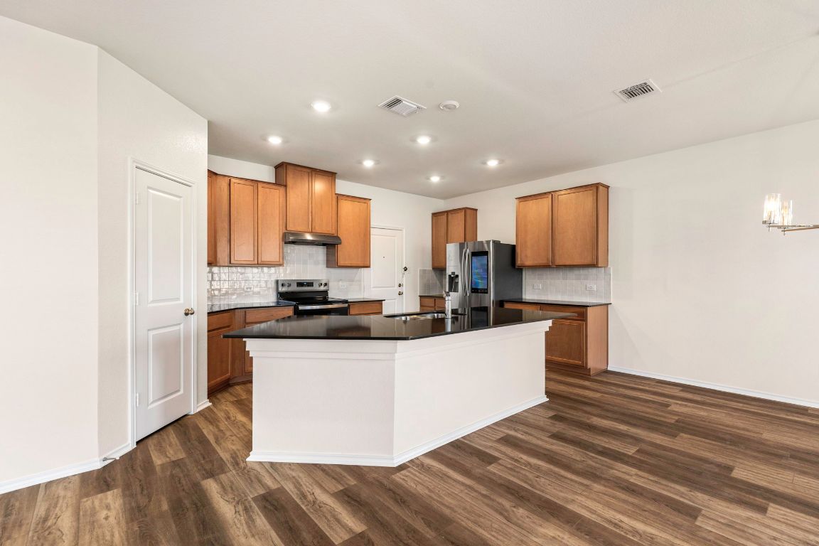 213 Skipping Stone Run Georgetown, TX 78628 - Photo 9 of 31 a kitchen with stainless steel appliances granite countertop a stove top oven a refrigerator a sink and dishwasher with wooden floor