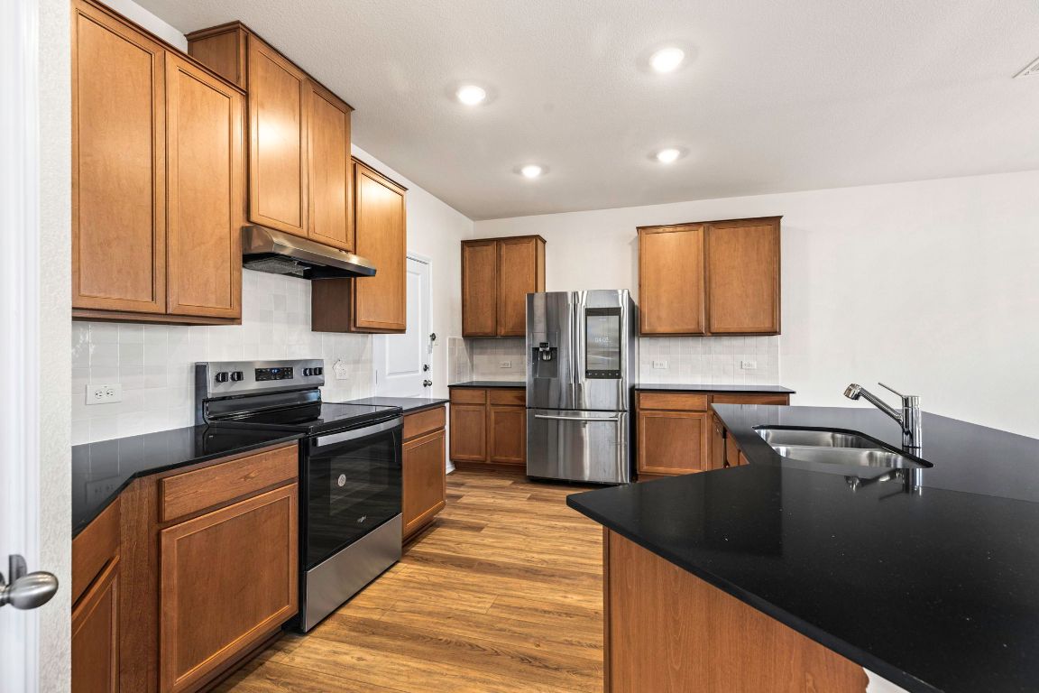 213 Skipping Stone Run Georgetown, TX 78628 - Photo 10 of 31 a kitchen with stainless steel appliances granite countertop a sink a stove and refrigerator