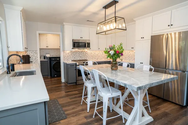 a kitchen with stainless steel appliances granite countertop a kitchen island hardwood floor sink stove dining table and chairs