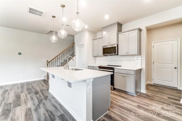 a kitchen with a sink a microwave a stove and white cabinets