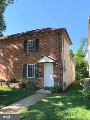 a backyard of a house with plants and large tree