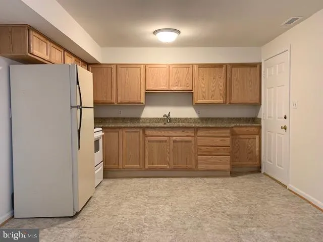 a kitchen with granite countertop a refrigerator sink and cabinets