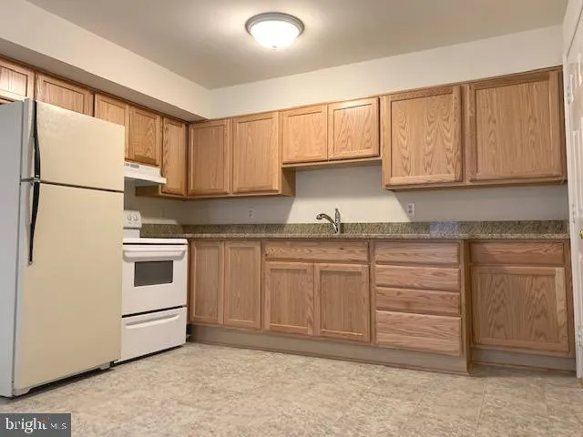 a kitchen with granite countertop white cabinets and white appliances