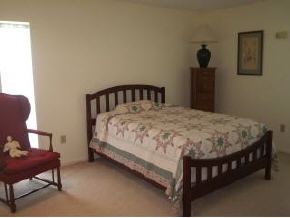 896 Ne Port Palm Bay, FL 32905 - Photo 8 of 9 a bed sitting in a bedroom next to a window with a chair