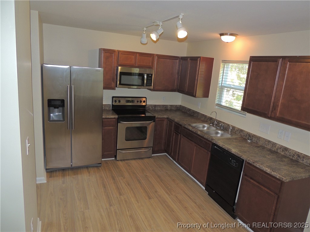 46 Hallow Oak Street Spring Lake, NC 28390 - Photo 5 of 22 a kitchen with stainless steel appliances granite countertop a refrigerator a sink a stove a microwave and wooden floors