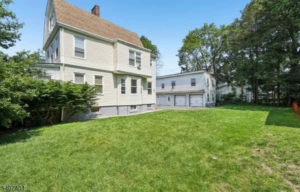 a view of a big house with a big yard and large trees