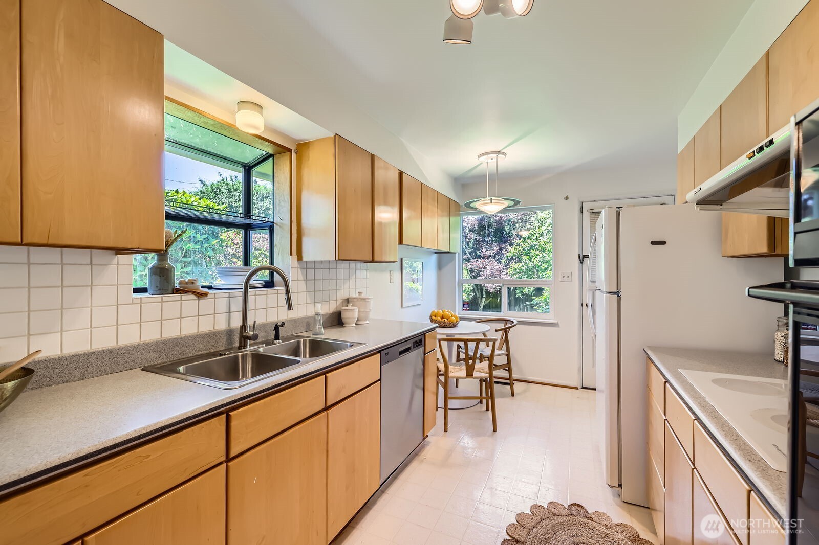 7924 South 112th Street Seattle, WA 98178 - Photo 9 of 40 a kitchen with a sink a counter top space stainless steel appliances a large window and cabinets