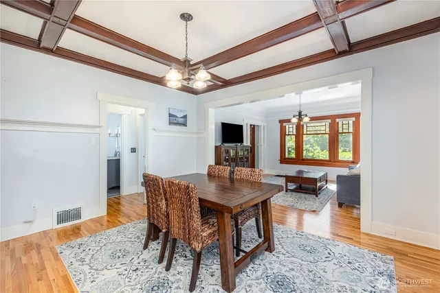 a dining room with wooden floor a chandelier a wooden table and chairs