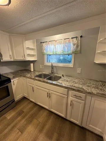 a kitchen with granite countertop white cabinets and white appliances