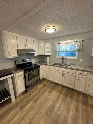 a kitchen with granite countertop a sink cabinets and stainless steel appliances