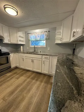 a kitchen with granite countertop a sink and white cabinets